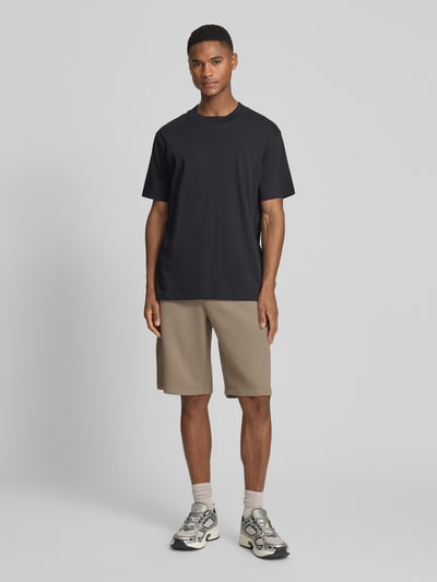 Männermodel trägt Bermudas mit Reißverschlusstaschen von EA7 Emporio Armani, Material-Mix mit Viskose-Anteil, Regular-Fit, Ganzkörperansicht von vorne.