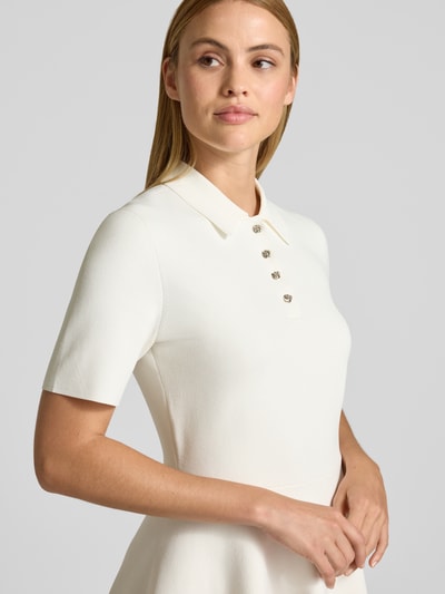 Frauenmodel trägt Polokleid mit kurzer Knopfleiste Modell 'RONDAA' von Ted Baker in Creme, Viskose-Mix, taillierter Schnitt, Nahaufnahme Oberkörper.