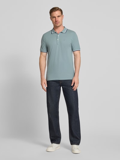 Männermodel trägt Relaxed Fit Poloshirt mit Kontraststreifen von Lindbergh aus reiner Baumwolle, Knopfleiste, Label-Stitching, Ganzkörperansicht von vorne. Rückenlänge bei Größe M: 67 cm.