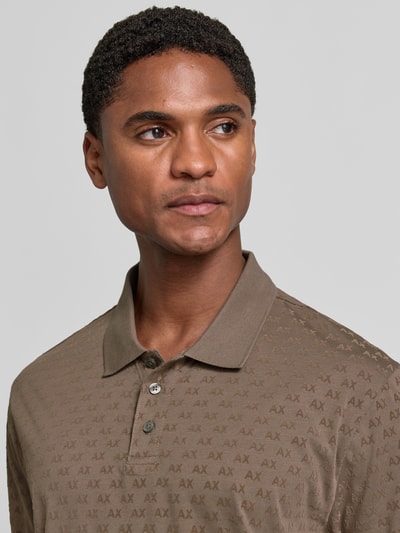 Männermodel trägt Regular Fit Poloshirt aus reiner Baumwolle von Armani Exchange in Braun mit Allover-Logo-Print, Nahaufnahme Oberkörper.