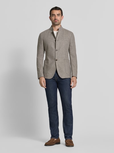 Męski model nosi Regular Fit Sakko mit Stehkragen Modell 'Hiro' von JOOP! COLLECTION z mieszanki bawełny, kolor beżowy, nakładane kieszenie, listwa guzikowa, długość tyłu 73 cm, szerokość w rozmiarze 50: 44 cm, długość rękawów 64 cm, Ganzkörperansicht von vorne.