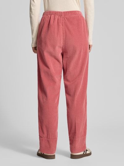 Frauenmodel trägt Stoffhose mit elastischem Bund Modell 'PADOW' von American Vintage in Rosa, lockerer Schnitt, reine Viskose, Ganzkörperansicht Rückansicht.