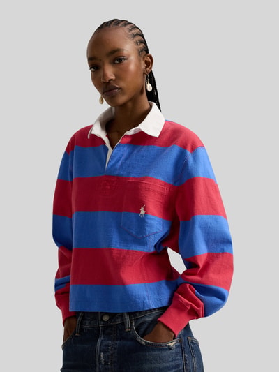 Frauenmodel trägt Regular Fit Poloshirt aus reiner Baumwolle von Polo Ralph Lauren in Blau-Rot gestreift mit Logo-Detail, Nahaufnahme Oberkörper.