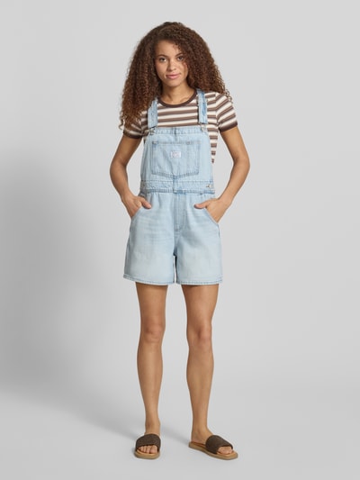 Modelka nosi Relaxed Fit Latzhose aus reiner Baumwolle od Levi's®, jasny denim, łatka z logo, luźny krój, bawełna, widok z przodu, cała sylwetka.