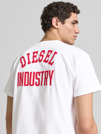 Männermodel trägt Regular Fit T-Shirt aus reiner Baumwolle von Diesel, weiß mit roter Label-Applikation, Kurzärmelig, Rückenlänge 70 cm, Ganzkörperansicht Rückansicht.