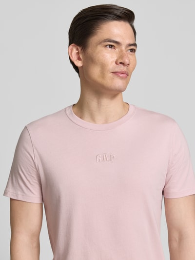 Männermodel trägt T-Shirt mit Rundhalsausschnitt und Label-Stitching von GAP in Rosa, Reine Baumwolle, Regular-Fit, Nahaufnahme Oberkörper.