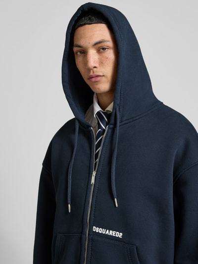 Männermodel trägt Oversized Sweatjacke aus Baumwoll-Mix von Dsquared2 in Dunkelblau mit Zweiwege-Reißverschluss, Känguru-Tasche und Kapuze, Nahaufnahme Oberkörper.