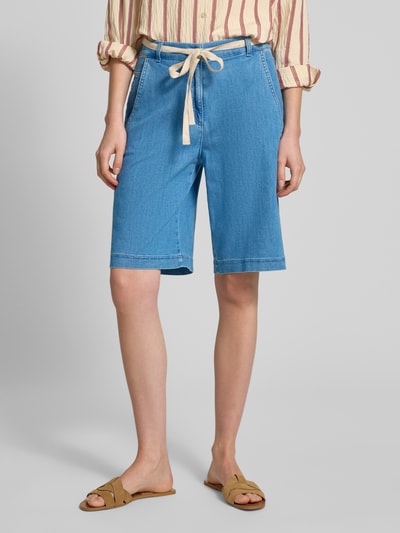 Frauenmodel trägt Wide Fit Bermuda aus Baumwoll-Mix von Raphaela By Brax in Denim-Optik mit Bindegürtel und seitlichen Eingrifftaschen, Nahaufnahme Oberschenkel.