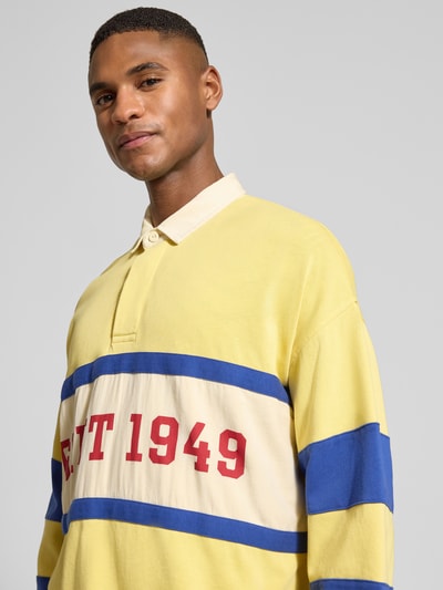 Męski model nosi Relaxed Fit Longsleeve mit Logo-Print od Gant, bawełna, polokragań, elastyczne mankiety, przód, zbliżenie górnej części.