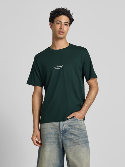 Männermodel trägt Regular Fit T-Shirt mit Logo-Print Modell 'Soho' von Jack & Jones aus Reine Baumwolle in Dunkelgrün, Ganzkörperansicht von vorne. Rückenlänge bei Größe M: 61 cm.
