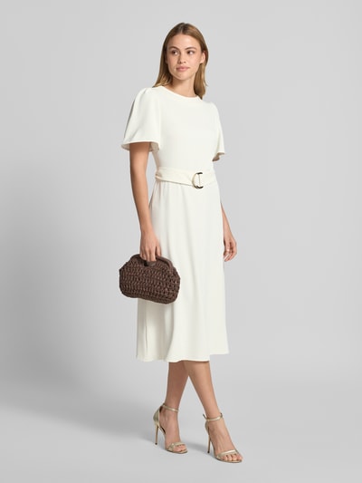 Frauenmodel trägt Cocktailkleid mit Gürtel und Rundhalsausschnitt von Rinascimento, Material-Mix mit Stretch-Anteil, Taillierter Schnitt, Midikleid, Rückseitiger Reißverschluss; cremefarbene Optik mit glattem Stoff, Ganzkörperansicht von vorne.