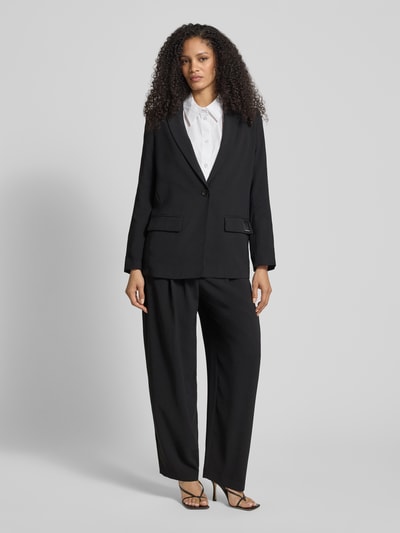 Frauenmodel trägt Relaxed Fit Blazer mit Reverskragen von ARMANI EXCHANGE in Schwarz mit Pattentaschen, Knopfverschluss, Ganzkörperansicht von vorne.