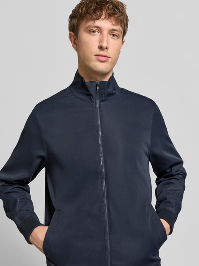 Męski model nosi Regular Fit Jacke mit Stehkragen Modell 'Hefi' von Blend z bawełny, ciemnoniebieska, wpuszczane kieszenie, zamek błyskawiczny, elastyczne wykończenia, długość tyłu w rozmiarze M: 71 cm, szerokość ramion w rozmiarze M: 46 cm, szerokość w rozmiarze M: 48 cm, długość rękawów w rozmiarze M: 25 cm, gładka tekstura, widok na górną część ciała z przodu