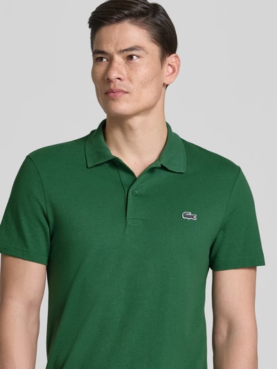 Männermodel trägt Regular Fit Poloshirt aus Baumwoll-Mix von Lacoste, Optik: Unifarben, Logo-Patch, Polokragen, Kurzarm, Nahaufnahme Oberkörper.