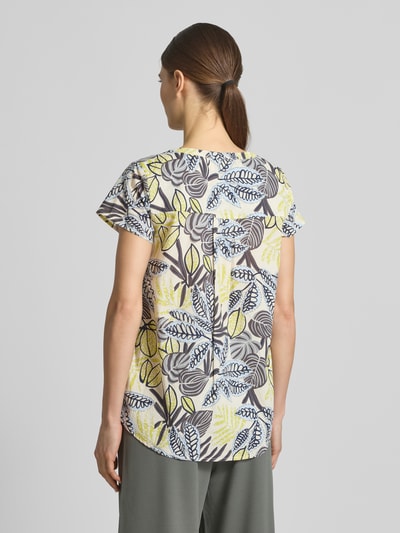 Frauenmodel trägt Relaxed Fit T-Shirt mit floralem Allover-Print von Soyaconcept aus reiner Baumwolle, Tunika-Ausschnitt, Rückansicht, Rückenlänge 66 cm, Ärmellänge 14 cm, Farben Gelb, Blau, Braun, Muster aus Blättern. Ganzkörperansicht Rückansicht.