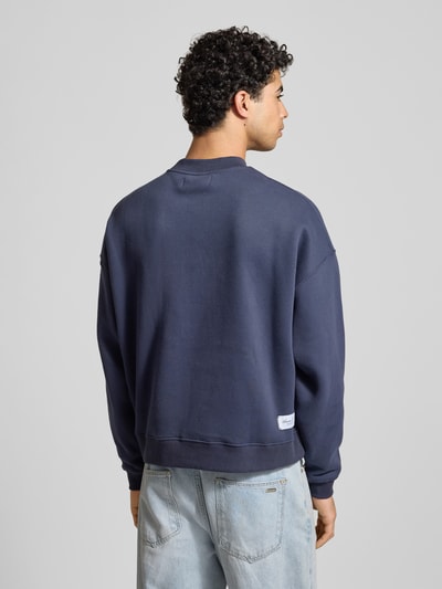 Männermodel trägt Sweatshirt mit Label-Print von ANOTHER COTTON LAB, Baumwoll-Mix, lockerer Schnitt, gerippte Abschlüsse, Rückansicht.