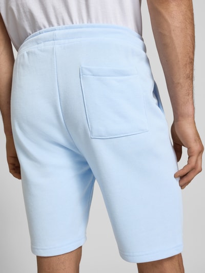 Męski model nosi Sweatshorts mit elastischem Bund Modell 'KARLOS' od Blend, bawełniany miks, krój regular fit, kolor jasnoniebieski, szerokość w rozmiarze M 42 cm, długość nogawki 21 cm, widok całej sylwetki z tyłu.
