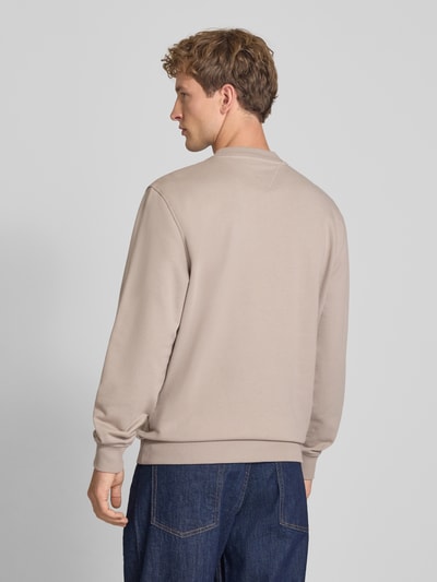 Męski model nosi Regular Fit Sweatshirt aus reiner Baumwolle von Tommy Jeans w kolorze beżowym, gładka tekstura, całkowity widok z tyłu.