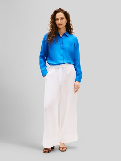 Frauenmodel trägt Relaxed Fit Langarmbluse aus reinem Leinen von Tommy Hilfiger, Optik: Unifarben, Passform: Relaxed-Fit, Hemdkragen, Logo-Stitching, Knopfleiste, Ärmelform: langarm, Ärmelabschluss: Manschette, Rumpfabschluss: abgerundet, Materialverarbeitung: Flammgarn, Material: Leinen, intensive blaue Farbe, glatte Textur, Ganzkörperansicht von vorne.