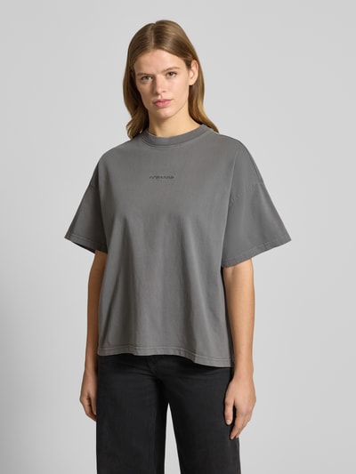 Frauenmodel trägt Oversized T-Shirt mit Label-Stitching von Pegador z bawełny, prążkowany okrągły dekolt, krój oversized, długość tyłu 60 cm, rozmiar S, kolor szary, widok całej sylwetki z przodu.