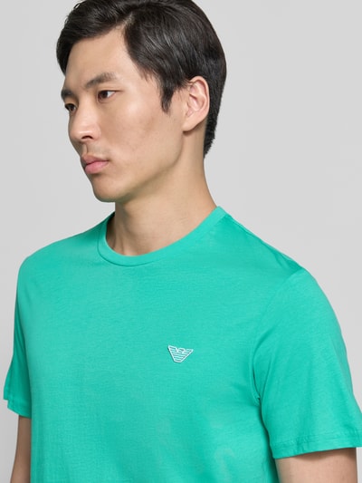 Männermodel trägt T-Shirt mit Logo-Patch und Rundhalsausschnitt von Emporio Armani in Reine Baumwolle, Modern Fit, Nahaufnahme Oberkörper.