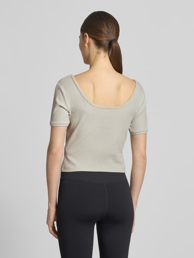 Młodzieżowy modelka nosi Cropped T-Shirt aus Lyocell-Mix Modell 'Circe' od Guess Activewear, jasnoszary, elastyczny materiał z bawełną, krój slim fit, logo-stitching, okrągły dekolt, długość tyłu w rozmiarze S: 31 cm, widok całej sylwetki z tyłu.