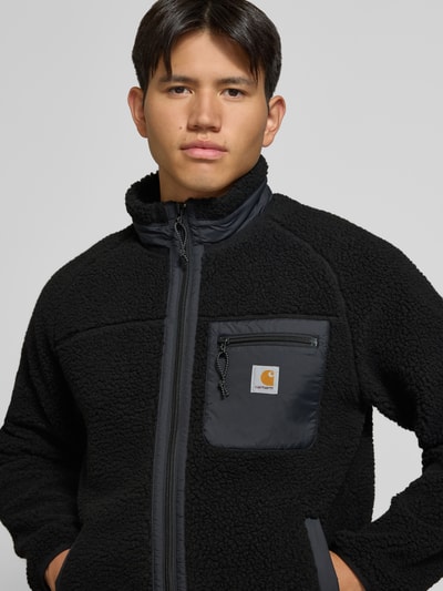 Männermodel trägt Teddyjacke mit Brusttasche Modell 'PRENTIS LINER' von Carhartt Work In Progress, Schwarz, Obermaterial Fleece, Nahaufnahme Oberkörper.