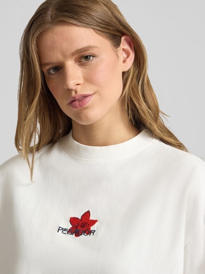 Frauenmodel trägt Oversized Fit T-Shirt mit Label-Stitching Modell 'MODRA' von Pegador aus reiner Baumwolle in Weiß, Nahaufnahme Oberkörper.