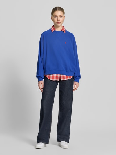 Frauenmodel trägt Regular Fit Sweatshirt aus Baumwoll-Mix von Polo Ralph Lauren in Unifarben Blau mit Logo-Stitching, Ganzkörperansicht von vorne.