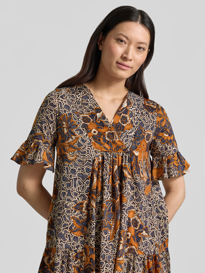 Frauenmodel trägt A-Linien Kaftankleid aus reiner Baumwolle Modell 'FUOCO' von Weekend Max Mara, Optik: Allover-Muster, Passform: A-Linie, Midi-Länge, Rundhals, Ärmelform: Kurzarm mit Volants, Materialverarbeitung: Jersey, Farbe Orange-Blau, Nahaufnahme Oberkörper.