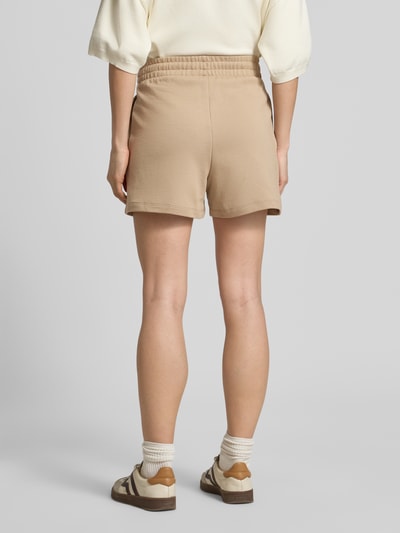 Frauenmodel trägt Relaxed Fit Shorts aus reiner Baumwolle Modell 'NINOSTA-2' von HUGO in Beige, elastischer Bund, Unifarbe, Baumwoll-Terry, Ganzkörperansicht Rückansicht.