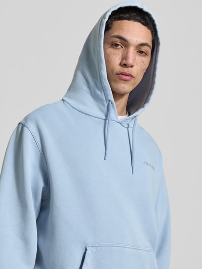 Männermodel trägt Hoodie mit Label-Stitching und Känguru-Tasche von Dickies in Hellblau, Baumwoll-Mix, Relaxed Fit, Nahaufnahme Oberkörper.