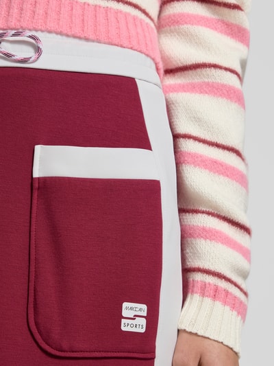 Frauenmodel trägt Straight Fit Midirock mit Logo-Print von Marc Cain, AufgesetzteTaschen, elastischer Bund mit Tunnelzug, Detailaufnahme