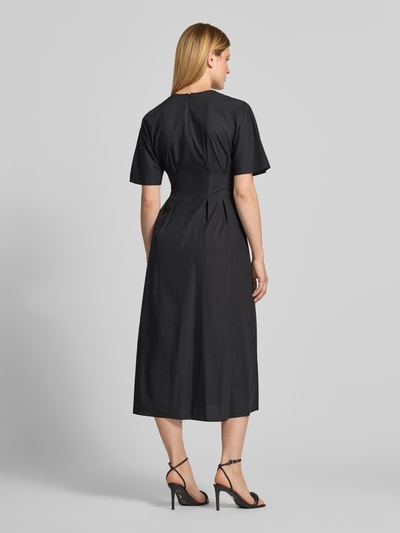 Frauenmodel trägt Midikleid aus Baumwoll-Lyocell-Mix Modell 'WORK' von MANGO in Schwarz, taillierte Passform, Kurzarm, Ganzkörperansicht Rückansicht.