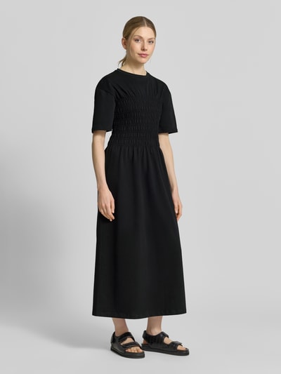 Frauenmodel trägt Midikleid mit Smok-Details von Jake*s Casual, reine Baumwolle, tailliert, schwarz, Ganzkörperansicht von vorne.