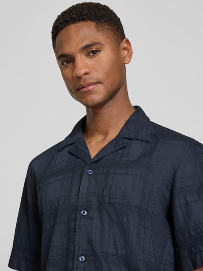 Männermodel trägt Regular Fit Freizeithemd aus reiner Baumwolle Modell 'RAYER_M' von BOSS Orange in Unifarben mit Struktur-Muster, Brusttasche, Reverskragen, einreihiger Knopfleiste, Kurzarm, Label-Applikation, Nahaufnahme Oberkörper.