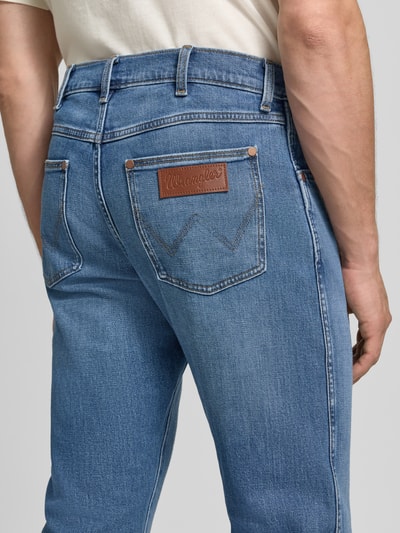 Mężczyzna nosi Regular Taper Jeans aus Baumwoll-Mix Modell 'Redford' od Wrangler, jasnoniebieski denim, gładka faktura, detal tylnej kieszeni, Ganzkörperansicht Rückansicht.