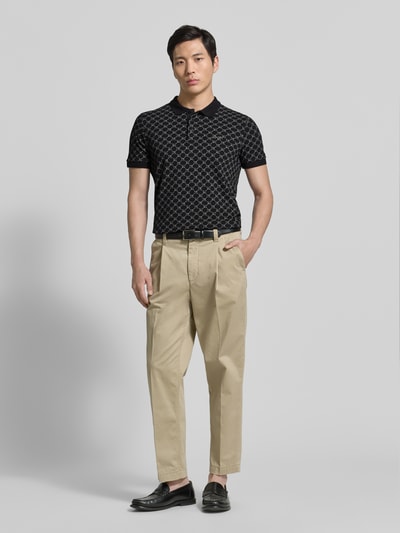 Männermodel trägt Slim Fit Poloshirt mit Logo-Muster Modell 'Paigam' von JOOP! Collection aus Baumwoll-Elasthan-Mix, Ganzkörperansicht von vorne.
