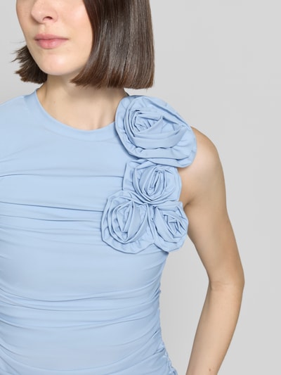 Frauenmodel trägt Cocktailkleid mit floralen Applikationen Modell 'DONA' von YAS aus hellblauem Satin, Körpernaher-Schnitt, Rundhalsausschnitt, Drapierungen, Nahaufnahme Oberkörper.