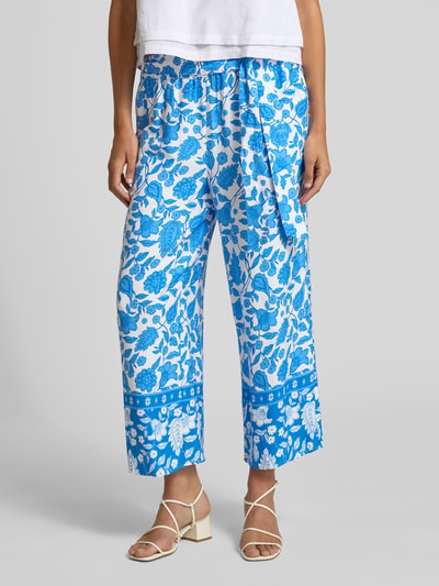 Frauenmodel trägt Straight Fit Stoffhose aus reiner Viskose von More & More mit Floraler-Print, Allover-Print, Elastischer Bund und Zierschleife, verkürzte Passform, leuchtende Blautöne, glatte Textur, Ganzkörperansicht von vorne.