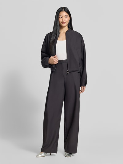 Frauenmodel trägt Regular Fit Barrel Leg Hose mit Viskose-Anteil Modell 'Hentessa-1' von HUGO in Schwarz mit Bundfalte, Ganzkörperansicht von vorne.