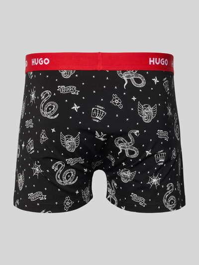 Männermodel trägt obcisłe bokserki Slim Fit Trunks aus Baumwoll-Mix im 3er-Pack Modell 'TRUNK TRPLET DESIGN' von HUGO, efekt: jednolity kolor, z napisem z logo, ściągacz: elastyczny, wielopak: 3 szt., wykończenie materiału: dżersej ze streczem, mieszanka bawełny; Ganzkörperansicht Rückansicht