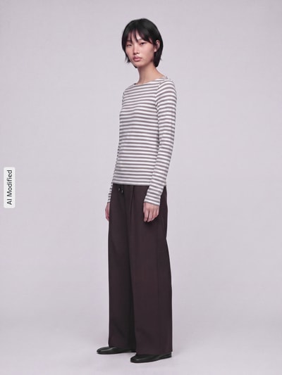 Kobiece modelka nosi Slim Fit Langarmshirt aus reiner Baumwolle von s.Oliver RED LABEL w paski, brązowe spodnie, jasne tło, całkowita sylwetka z przodu, KI-modifiziertes Bild