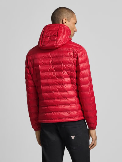 Männermodel trägt rote Steppjacke mit Kapuze und Zweiwege-Reißverschluss Modell 'Charles' von Blauer Usa, Ganzkörperansicht Rückansicht, Regular Fit, Label-Detail, Rückenlänge 65 cm, Schulterbreite 47 cm, Brustweite 55 cm, Ärmellänge 65 cm.