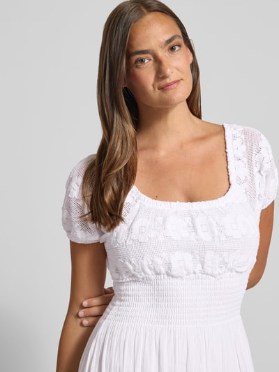 Frauenmodel trägt Midikleid mit Smok-Details und Rundhalsausschnitt von Apricot aus Reine Baumwolle, Weiß, taillierter Schnitt, Nahaufnahme Oberkörper. Rückenlänge bei Größe S: 124 cm, Brustweite bei Größe S: 24 cm, Ärmellänge bei Größe S: 20 cm.