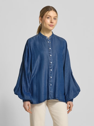 Kobiece model prezentuje bluzkę jeansową Oversized Jeansbluse aus Lyocell Modell 'C_BETTA' od BOSS Orange, tkanina stylizowana na denim, krój oversized, stójka, na całej długości listwa guzikowa, aplikacja z metką, rękawy nietoperzowe, zakończenie rękawów mankietem, materiał: lyocell, kolor niebieski, faktura gładka, pełny widok z przodu.