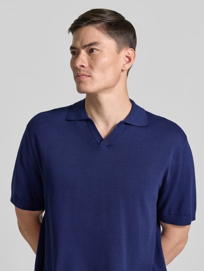 Männermodel trägt Relaxed Fit Poloshirt aus reiner Baumwolle Modell 'TORINO' von SELECTED HOMME in Dunkelblau, Nahaufnahme Oberkörper.