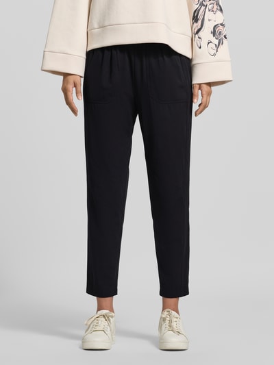 Frauenmodel trägt Hose mit elastischem Bund und Eingrifftaschen von Marc Cain, schwarze Farbe, Regular Fit, Material-Mix, Nahaufnahme Oberkörper.