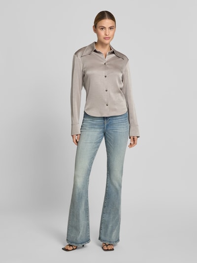 Frauenmodel trägt Flared Fit Jeans mit Logo-Detail von Diesel aus elastischem Baumwoll-Mix, 5-Pocket-Design, mittelblaue Waschung, Ganzkörperansicht von vorne.
