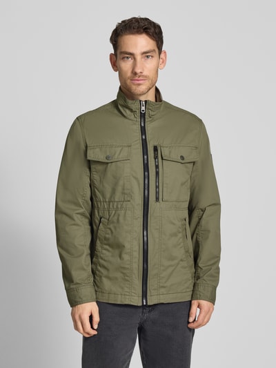 Männermodel trägt Regular Fit Jacke aus reiner Baumwolle von Tom Tailor in Olive, Two-Tone-Optik, Reißverschluss, Brust- und Seitentaschen, Ganzkörperansicht von vorne.